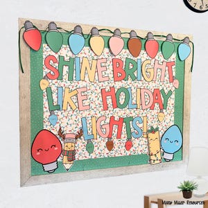 May include: A framed holiday-themed bulletin board with the text "Shine Bright Like Holiday Lights!" Colorful light bulb cutouts and illustrations decorate the board. The frame is light gray, and the background is a pattern of Christmas lights.