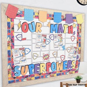 May include: A framed classroom bulletin board with the words "OUR MATH SUPERPOWERS!" in colorful letters. The board features student name cards and comic-style graphics. Decorative pennants in various colors are strung across the top.