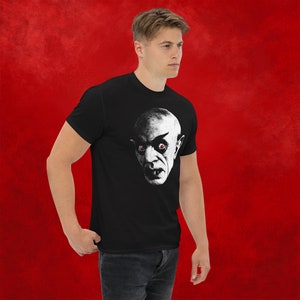 May include: A black t-shirt with a white graphic of a vampire with red eyes. The vampire's face is shown in profile.