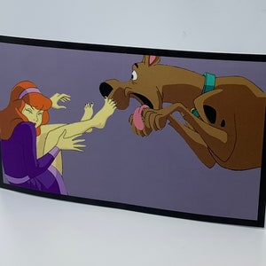 May include: A cartoon illustration of a purple-clad woman with red hair being tickled by a brown and yellow dog with a green collar. The dog is sticking its tongue out and has a surprised expression.
