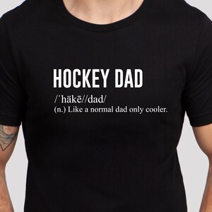 K&ouml;nnte beinhalten: Schwarzes T-Shirt mit wei&szlig;em Text, der "HOCKEY DAD /'h&auml;kē//dad/ (n.) Like a normal dad only cooler." lautet.