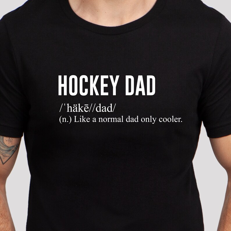 K&ouml;nnte beinhalten: Schwarzes T-Shirt mit wei&szlig;em Text, der "HOCKEY DAD /'h&auml;kē//dad/ (n.) Like a normal dad only cooler." lautet.