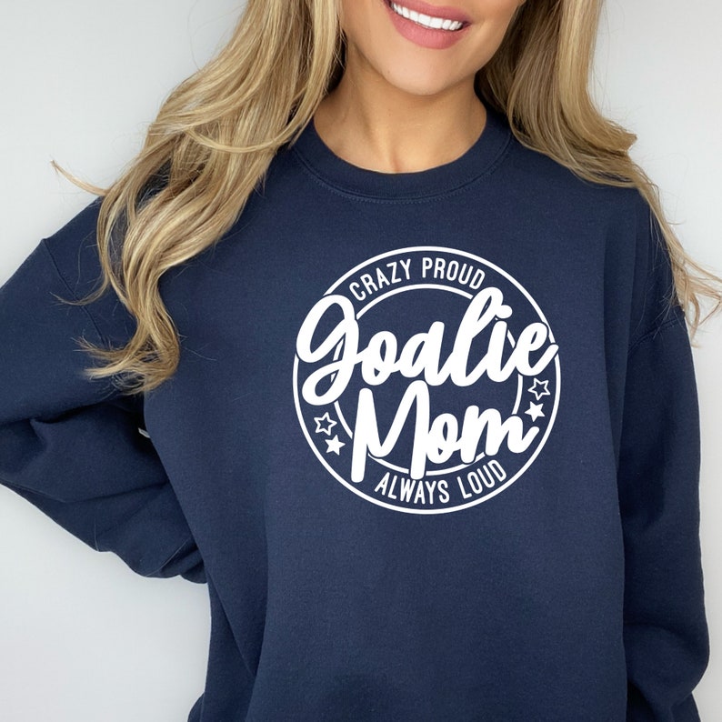 K&ouml;nnte beinhalten: Marineblauer Sweatshirt mit einem wei&szlig;en Kreis-Motiv, auf dem "Crazy Proud Goalie Mom Always Loud" steht.