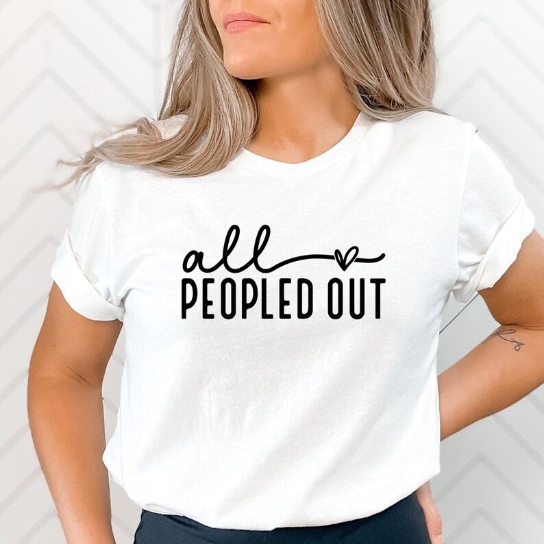 May include: White t-shirt with black text that reads "all - heart - peopled out".