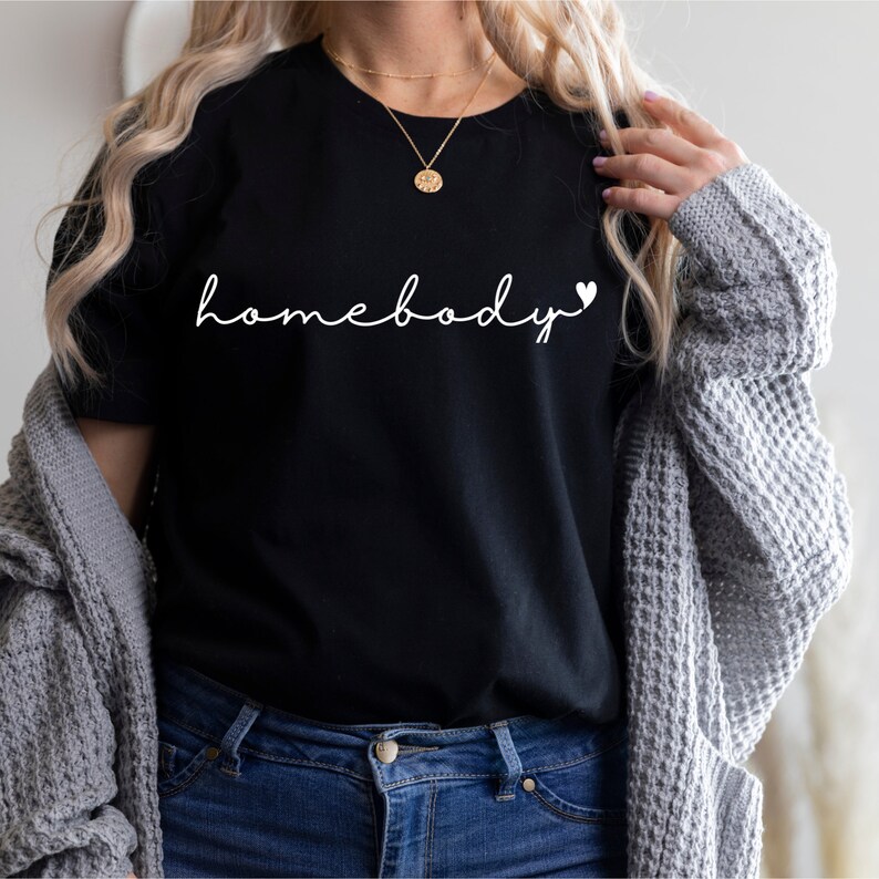 May include: A black t-shirt with the text "homebody" in white cursive lettering and a small white heart.