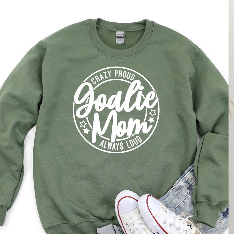 K&ouml;nnte beinhalten: Gr&uuml;nes Sweatshirt mit einem wei&szlig;en Kreis-Motiv, auf dem "Crazy Proud Goalie Mom Always Loud" steht.