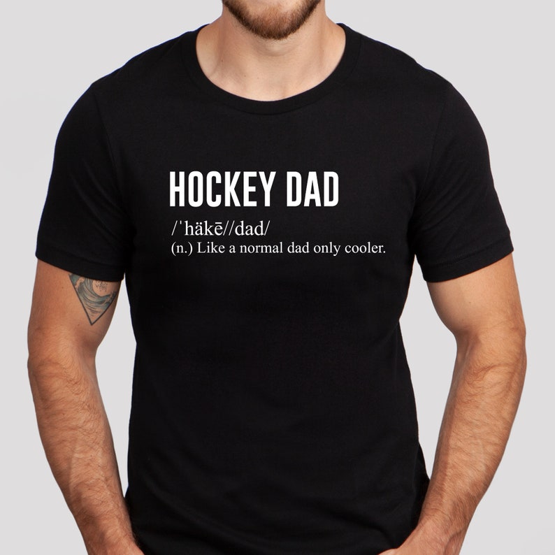 K&ouml;nnte beinhalten: Schwarzes T-Shirt mit wei&szlig;em Text, der "HOCKEY DAD /'h&auml;kē//dad/ (n.) Like a normal dad only cooler." lautet.