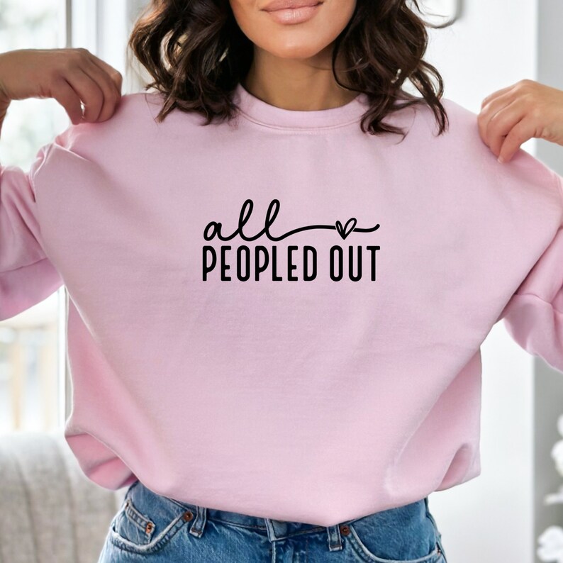 May include: Pink sweatshirt with the text "all &hearts; peopled out" in black.