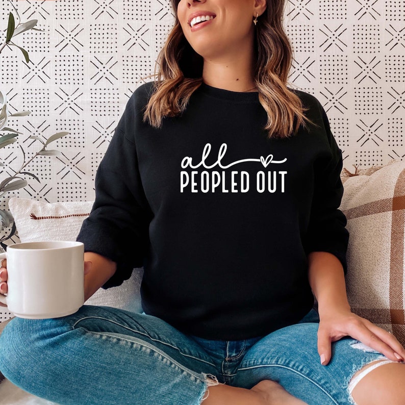 May include: A black sweatshirt with the text "all peopled out" in white lettering with a small heart symbol.