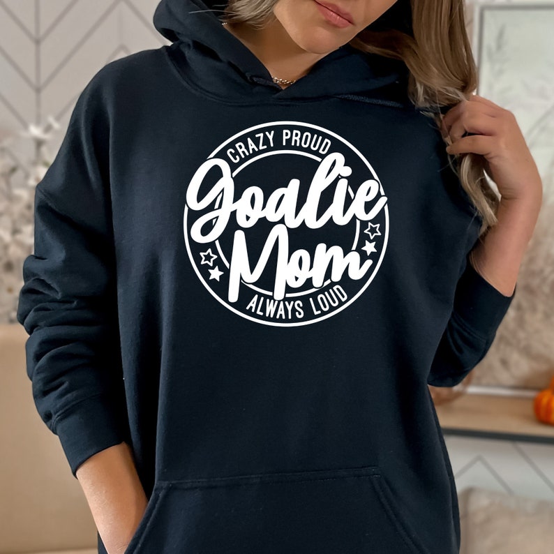 K&ouml;nnte beinhalten: Schwarzer Hoodie mit einem wei&szlig;en Kreis-Motiv, auf dem "Crazy Proud Goalie Mom Always Loud" steht.