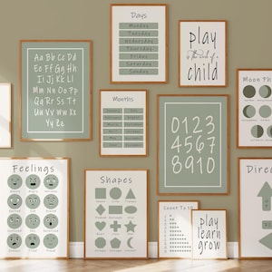 May include: A collection of framed educational posters with a neutral color palette. The posters display the alphabet, numbers, shapes, feelings, days of the week, months, moon phases, and directions. The text "play is the work of a child" is also displayed.