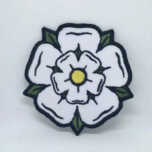 May include: White embroidered flower patch with green leaves and a yellow centre. The flower is outlined in black.