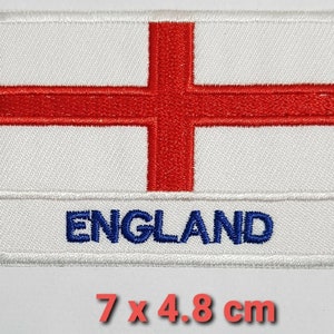 May include: White embroidered patch with a red cross and the word "ENGLAND" in blue lettering. The patch measures 7 by 4.8 centimetres.