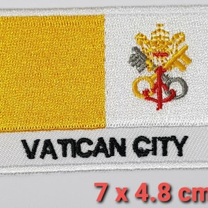 Könnte beinhalten: Ein weißer und gelber gestickter Aufnäher mit dem Text "VATICAN CITY" und einem Wappen mit Schlüsseln, einer Papstkrone und einem Anker. Der Aufnäher misst 7 x 4,8 Zentimeter.