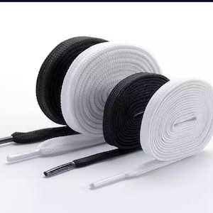 May include: Four spools of shoelaces, two black and two white. The shoelaces are flat and woven.