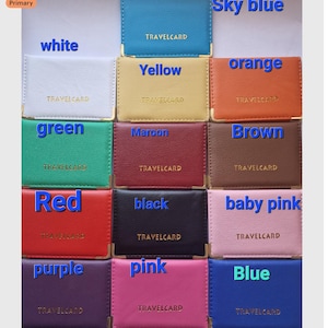 以下が含まれることがあります： スカイブルー、白、黄色、オレンジ、緑、マルーン、茶色、赤、黒、ベビーピンク、紫、ピンク、青など、さまざまな色合いのカラフルなTRAVELCARDホルダーのコレクション。各ホルダーには金の角があり、「TRAVELCARD」の文字が印刷されています。