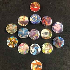Peut inclure: Un ensemble de 16 boutons ronds représentant des personnages de Pokémon. Les boutons présentent divers personnages de Pokémon, notamment Pikachu, Dracaufeu et Carapuce. Les boutons sont colorés et ont une finition brillante.