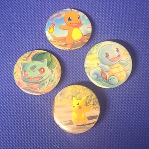Może przedstawiać: Cztery okrągłe guziki z różnymi postaciami Pokemonów. Guziki są kolorowe i przedstawiają obrazy Pikachu, Squirtle, Bulbasaura i Charmandera.