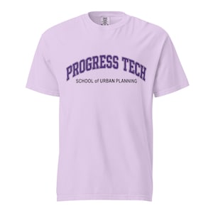 Puede incluir: Una camiseta de manga corta de color morado claro con el texto morado oscuro PROGRESS TECH arqueado sobre las palabras SCHOOL of URBAN PLANNING en una fuente más pequeña y recta. La camiseta tiene cuello redondo y corte estándar.