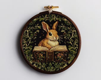 Peut inclure: Un lapin brun assis sur un livre avec un motif floral vert foncé et brun. Le lapin regarde le livre. Le livre est fermé et a une reliure dorée.