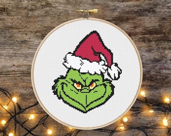 May include: A green Grinch character wearing a red Santa hat with white trim. The Grinch is looking directly at the viewer with a mischievous expression.