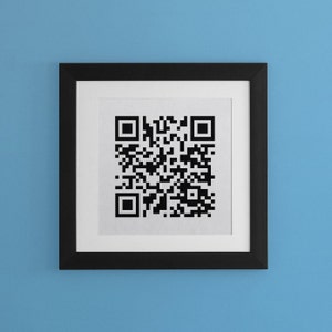 May include: A black framed picture with a white mat and a black and white QR code in the center.