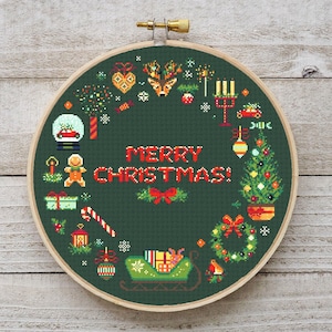 Puede incluir: Un bastidor de punto de cruz con un diseño navideño festivo. El diseño presenta un fondo verde con las palabras "MERRY CHRISTMAS!" en rojo. El diseño incluye un árbol de Navidad, renos, regalos y un trineo.