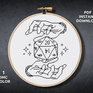 May include: Black and white cross stitch pattern of two hands holding a twenty-sided die. The die is in the center of the design and has numbers 1 through 20 on its faces. The hands are stylized and have a simple design. The background is white.