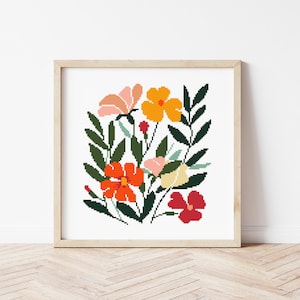 Può includere: Un motivo a punto croce incorniciato che presenta un bouquet di fiori colorati in tonalità di arancione, rosso, rosa e giallo. I fiori sono circondati da foglie e steli verdi.