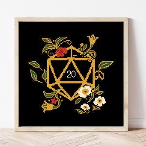 May include: A framed cross-stitch depicting a gold twenty-sided die, embellished with flowers. The die shows the number 20 in white. The background is black, and the flowers are red and white.