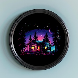 May include: A pixel art print of a cabin in a forest at night, framed in a black circular frame. The scene features a cabin with lit windows, surrounded by dark green trees under a starry sky with a crescent moon. The color palette includes shades of purple, pink, and blue.