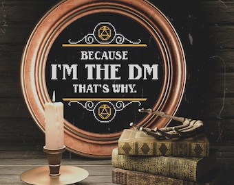 May include: A framed sign with the text "BECAUSE I'M THE DM THAT'S WHY." A lit candle in a gold holder, and a stack of antique books are on a wooden surface. A skeleton hand rests on the books. The frame is round and bronze.