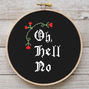 May include: Black embroidery hoop with white text that reads "Oh, Hell No" in a gothic font. There are three red flowers with green stems on the top left of the hoop.