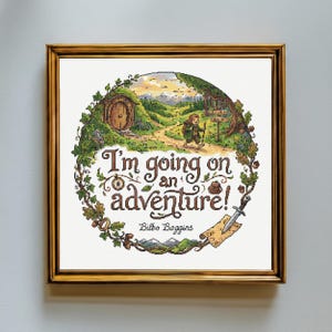 May include: A framed cross-stitch embroidery featuring a circular landscape with a hobbit hole, a traveler, and the text "I'm going on an adventure!" with "Bilbo Baggins" below. The design includes a compass, a sword, and a map, all framed in gold.