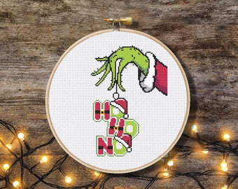 May include: A green Grinch hand holding a string of ornaments that spell "HO HO NO" in red and green. The ornaments are decorated with Santa hats.