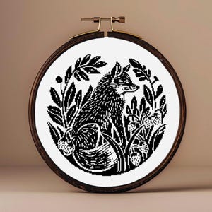 Puede incluir: Aro de bordado en blanco y negro con un zorro rodeado de hojas y bayas. El zorro mira hacia la izquierda.