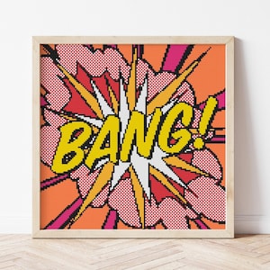 Pode incluir: Uma impressão emoldurada de arte pop com a palavra "BANG!" em amarelo, em um fundo laranja, vermelho e rosa. A obra apresenta uma explosão em estilo de história em quadrinhos.