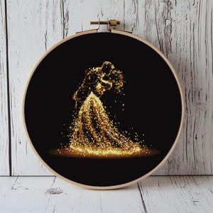 May include: A cross-stitch embroidery hoop featuring a silhouette of a couple embracing, rendered in shimmering gold against a black background. The design is set within a wooden embroidery hoop, creating a striking contrast.