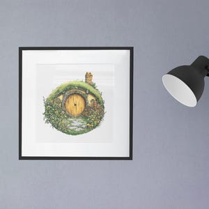 K&ouml;nnte beinhalten: Eine gerahmte Illustration eines Hobbitlochs mit einem runden, gr&uuml;nen, grasbewachsenen Dach und einer gelben T&uuml;r. Das Loch ist von gr&uuml;nen Pflanzen und Blumen umgeben.