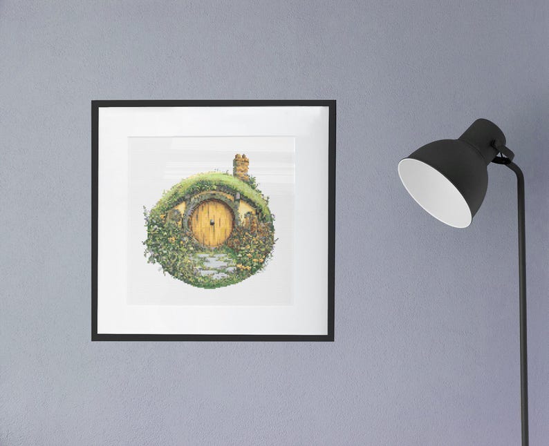 K&ouml;nnte beinhalten: Eine gerahmte Illustration eines Hobbitlochs mit einem runden, gr&uuml;nen, grasbewachsenen Dach und einer gelben T&uuml;r. Das Loch ist von gr&uuml;nen Pflanzen und Blumen umgeben.