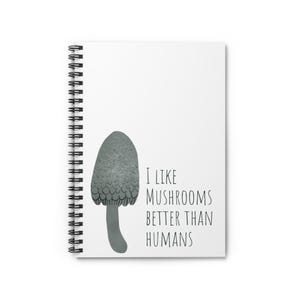 Puede incluir: Cuaderno de espiral blanco con una ilustración de hongo gris y el texto "I LIKE MUSHROOMS BETTER THAN HUMANS" en negro. El cuaderno tiene un diseño minimalista, perfecto para tomar notas o escribir.
