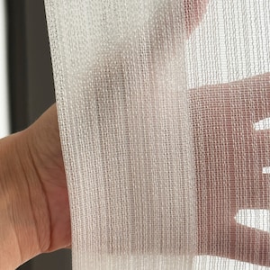 May include: White sheer curtain fabric with a fine weave. The fabric is translucent and has a slightly textured surface.