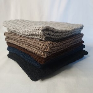May include: A stack of five crocheted squares in different colors, including gray, brown, dark blue, and black.