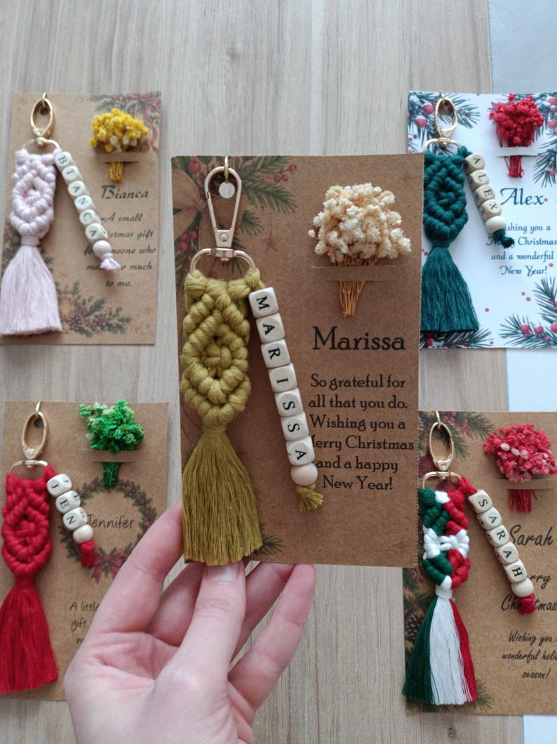 Collection of personalized Christmas macrame keychains shown in different festive, pastel, neutral, and colorful combinations. Each handmade keychain can be customized with a name, one or more rope colors, and a metal hook style. Add an optional personalized holiday card or dried flower for a complete gift. Perfect for bulk Christmas orders, employee gifts, coworker gifts, team presents, family gifts, stocking stuffers, and holiday party favors.