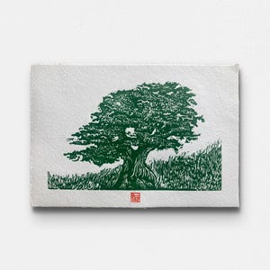 Peut inclure: Impression d'art verte et blanche d'un grand arbre avec un feuillage touffu et un tronc texturé. L'arbre est sur fond blanc avec de l'herbe verte à la base. Un petit tampon rouge est dans le coin inférieur droit.