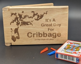 Puede incluir: Una caja de madera con un mapa de un lago y el texto "It's A Great Day For Cribbage on the Chain of Lakes".