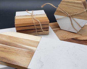 Puede incluir: Conjunto de cuatro posavasos de madera con tapa de mármol blanco, atados con cuerda. Los posavasos se muestran en una bandeja de servir más grande de madera y mármol blanco.