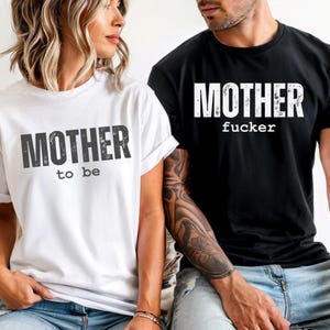 Puede incluir: Dos camisetas, una blanca y otra negra. La camiseta blanca tiene el texto "MOTHER to be" y la camiseta negra tiene el texto "MOTHER fucker". El texto está en negrita, con un efecto desgastado.