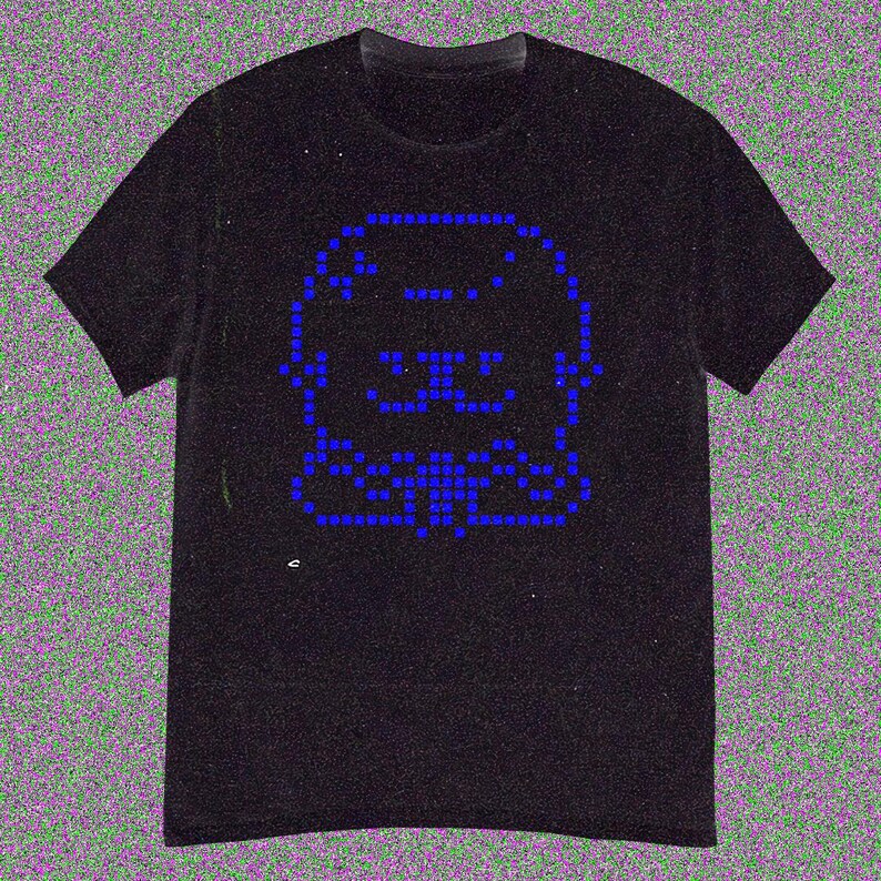 May include: Black t-shirt featuring a pixelated blue graphic of a dog's face. The design is made up of small blue squares, creating a retro, digital aesthetic. The shirt has a classic crew neck and short sleeves.