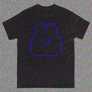 May include: Black t-shirt with a blue pixelated design depicting two figures in an embrace. The design is outlined with small blue squares and has additional blue dots within the figures. The shirt has a crew neck and short sleeves.
